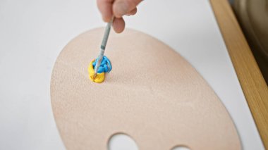 Çekici orta yaşlı beyaz erkek sanatçı yaratıcı çizim dersleri alırken kapalı bir stüdyoda palet üzerine renk karıştırıyor.