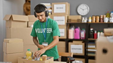 Gülümseyen, kendine güveni tam genç Latin bir adam vaktini hayır kurumunda gönüllü olarak geçiriyor. Yiyecek ürünlerini paketlere koyup akortları karıştırıyor.