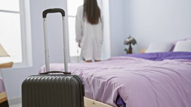 Pijamalı, genç ve güzel bir İspanyol kadın. Arkaya bakıyor. Otel odasındaki pencereye bakıyor.