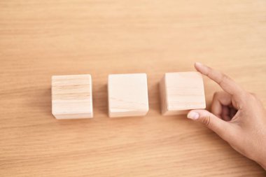 Genç, güzel, İspanyol bir iş kadını masada, ofisinde tahta küplerle oturuyor.