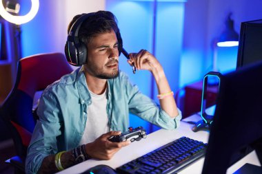 Oyun odasında İspanyol asıllı genç adam video oyunu oynuyor.