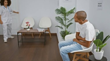 Hastanın mide ağrısına bakan doktor, birlikte bir sandalyede otururken kliniğin bekleme odasında acil bir durum olduğunu belirtiyor.