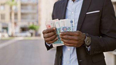 Takım elbiseli bir Afrikalı, şehir ortamında Çin yuanı sayıyor..