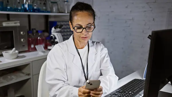 Latynoska Kobieta Średnim Wieku Okularach Fartuchu Laboratoryjnym Używająca Smartfona Nowoczesnym — Zdjęcie stockowe
