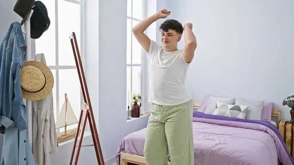 A happy young man dancing alone in his bright bedroom, expressing freedom and joy indoors.