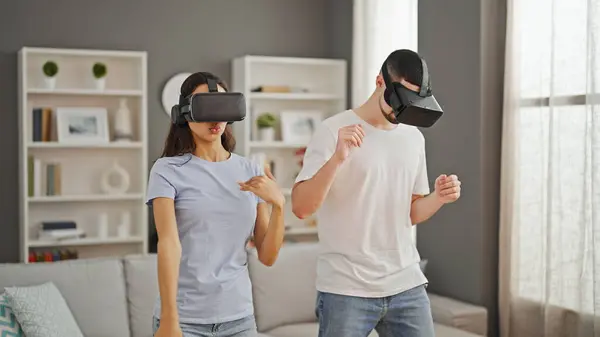 Beautiful couple in love, gaming together at home, using virtual reality glasses for an immersive dance video game experience