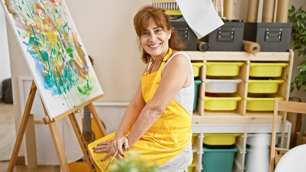 Mujer Madura Artista Pintando Sobre Lienzo Estudio Sonriendo Delantal Amarillo — Foto de Stock