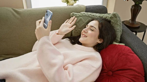 一位年轻的高加索女人舒服地躺在舒适的客厅里的沙发上 享受着视频通话的乐趣 — 图库照片