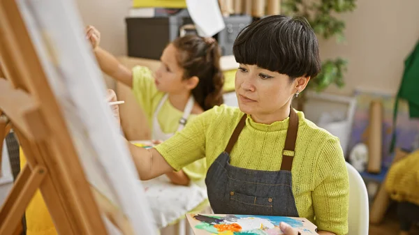 Mother and daughter drawing together, artist teacher inspiring creativity in indoors art studio class