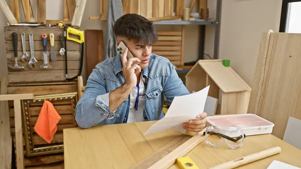 Handsome Young Hispanic Man Skilled Carpenter Engrossed Reading Document While — Stock Photo, Image
