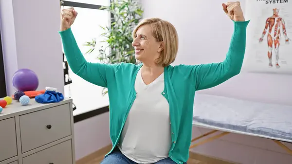 一位面带微笑的中年金发女子在疗养院的病房里伸展肌肉 展示出她的力量和积极向上的一面 — 图库照片