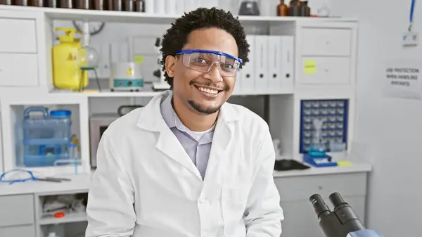 stock image Smiling man wearing lab coat and safety goggles in scientific laboratory setting