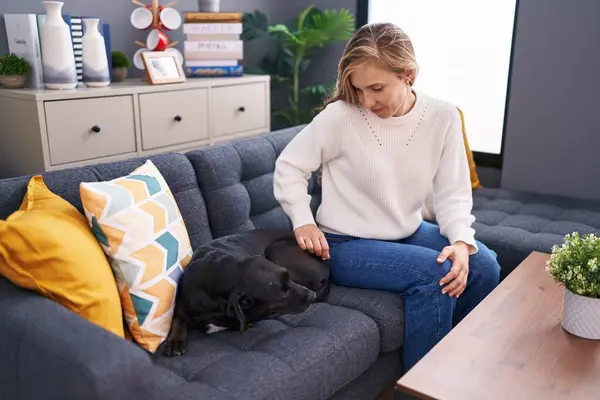 Young blonde woman smiling confident sitting on sofa with dog at home