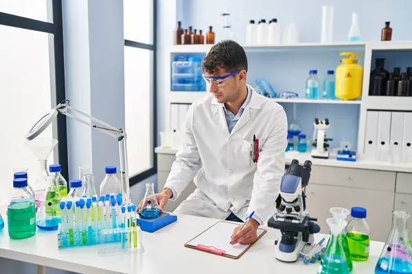 Young Hispanic Man Scientist Weighing Liquid Writing Document Laboratory — Stock Photo, Image