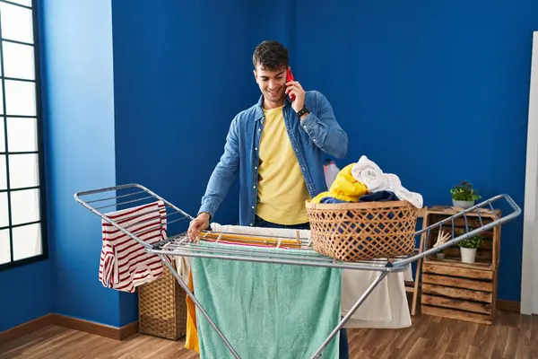 Young Hispanic Man Talking Smartphone Hanging Clothes Clothesline Laundry Room — Stock Photo, Image