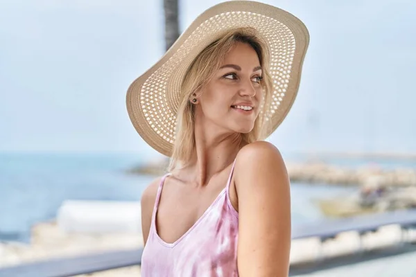 Young blonde woman tourist smiling confident standing at seaside