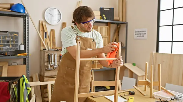 Focused Young Man Beard Wearing Safety Goggles Apron Polishes Wooden — Stock Photo, Image