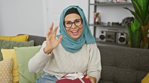 Eine Lächelnde Reife Frau Hijab Hält Eine Herzförmige Geschenkschachtel Der — Stockvideo