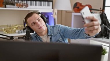 Müzik stüdyosunda selfie çeken kulaklık takan yakışıklı bir adam.