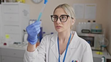 Odaklanmış bir kadın bilim adamı laboratuvar ortamında bir pipet inceliyor, bu da araştırma ve sağlık hizmetlerini gösteriyor ki....