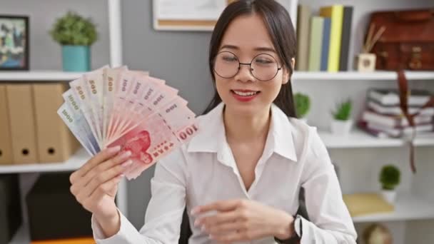 Молодая Китаянка Предприниматель Держит Банкноты Юаня Улыбаясь Показывая Рукой Пальцем — стоковое видео