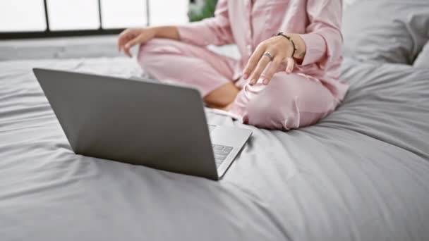 一位穿着粉色睡衣的年轻女子拿着笔记本电脑坐在床上沉思 描绘着在舒适的卧室里放松的情景 — 图库视频影像