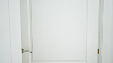 Şaşırmış, dövmeli bir adam beyaz bir kapıdan içeri bakıyor. Ev ortamında bir dizi duyguyu ifade ediyor..