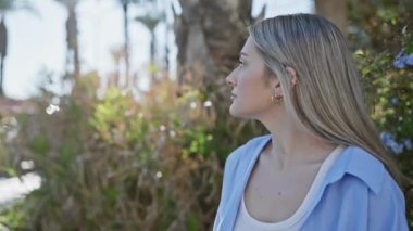 Huzurlu sarışın bir kadın, bereketli bir bahçe parkında huzurun tadını çıkarıyor..