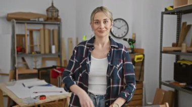 İyi donanımlı bir marangozluk atölyesinde duran, kendine güveni tam genç bir kadın güzellik ve becerinin bir karışımını somutlaştırıyor..