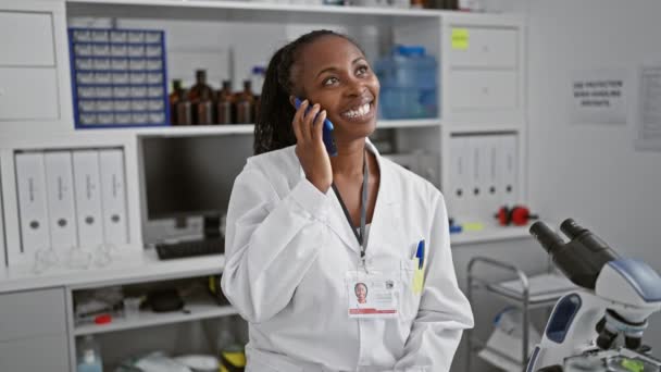 アフリカ系アメリカ人女性科学者 実験室で電話で話すコート — ストック動画