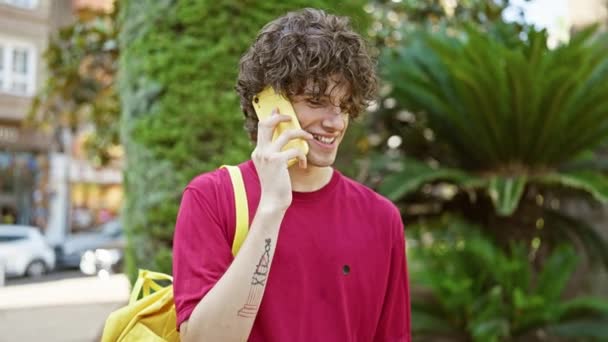 Усміхнений Молодий Чоловік Кучерявим Волоссям Має Телефонну Розмову Відкритому Повітрі — стокове відео