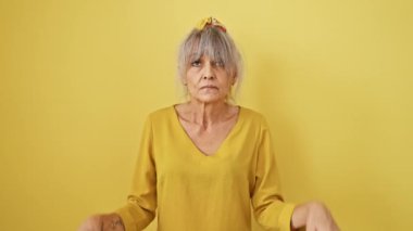 Gri at kuyruklu, üzgün, orta yaşlı kadın mahvolmuş görünüyor. Depresyonda, üzgün, sarı bir arka plana karşı bir yön gösteriyor, parmakları ağır bir yük taşıyor..