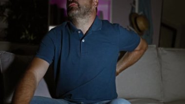 Kanepede sırt ağrısı çeken gri saçlı, olgun bir adam..