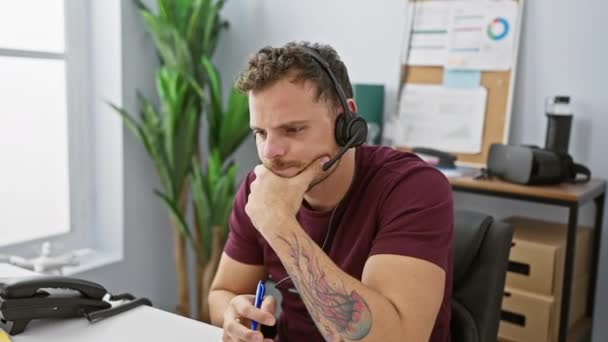 Konzentrierter Mann Mit Headset Und Tätowierung Hört Schreibtisch Heller Büroumgebung — Stockvideo