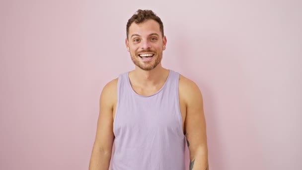 袖のないTシャツの陽気な若者は 孤立したピンクの背景の上に喜んで指し 微笑んで — ストック動画