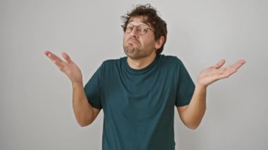 Kafası karışmış, gözlüklü genç bir İspanyol. Kolları omuz silkerek kaldırmış. Belirsiz duygular içinde kaybolmuş, izole edilmiş beyaz arka planda duruyor..