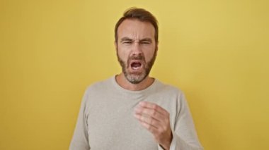 Yorgun İspanyol adam esniyor, sıkılmış yüz ifadesi ortaya çıkıyor. Uykusuzluk beni ele geçiriyor. Tek başına çekim, izole edilmiş sarı arkaplan