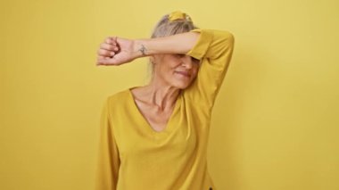 Midilli kuyruklu, şakacı, orta yaşlı bir kadın, neşeli bir şekilde yüzünü gösteriyor. Bir yuhalama oyununda, sarı izole edilmiş arka planda, heyecanlı bir neşeyi paylaşıyor..