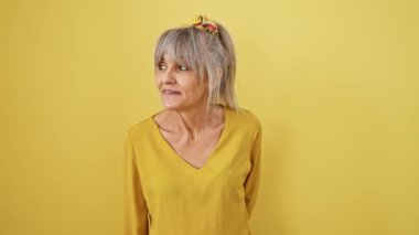 Fısıldayan sırlar, midilli kuyruklu orta yaşlı kadın gri saçlı kadın sulu bir dedikodu anlatıyor, ağzı kapalı, izole edilmiş sarı arka plan