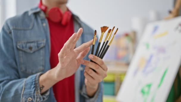 Young Bearded Man Holding Paintbrushes Bright Art Studio Displaying Creativity — Stock Video
