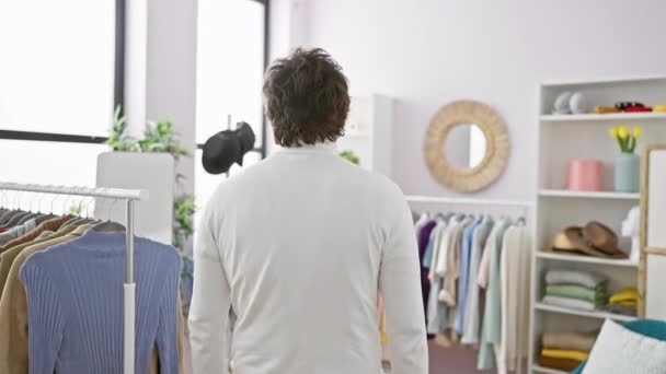 一个满脸笑容 一头卷发的年轻人站在一间整洁的房间里 房间里有衣架和装满时尚物品的架子 — 图库视频影像
