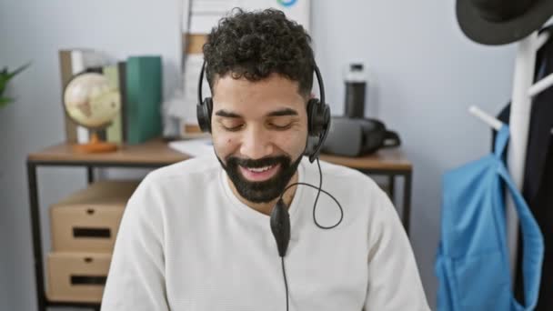 一个快乐而惊慌的男人 留着胡子 头戴耳机 笑着在办公室里干活 — 图库视频影像