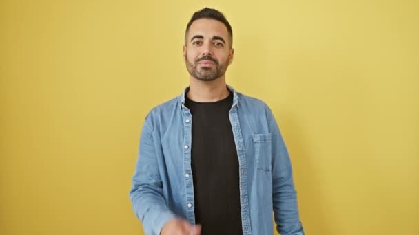 デニムシャツの陽気な若いヒスパニックの男はカメラに愛のキスを送信し 黄色の壁の背景にセクシーな自信を放射する — ストック動画