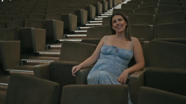 Uśmiechnięta Młoda Kobieta Siedzi Sama Przestronnej Sali Teatralnej Wygodnymi Fotelami — Wideo stockowe