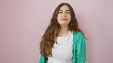Büyüleyici genç İspanyol kadın, mutlulukla ışıldıyor, buraya bir jest yapıyor, izole pembe arka planda duruyor. Çekiciliğin ve cazibenin sembolü..