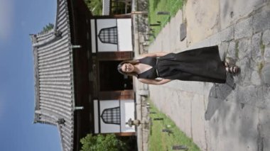 Gözlüklü neşeli, güzel İspanyol kadın kameraya doğru yürüyor, Kodaiji Tapınağı 'nda gülümseyen bir yüzle poz veriyor, Kyoto - geleneksel Japon bahçesinin ortasında neşeli bir güven ve eğlence portresi