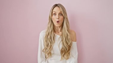 Şok olmuş genç bir kadının yüzü! Güzel sarışın, korkmuş ve şaşırmış bir ifade, ağzı açık, izole edilmiş pembe bir arka plan için inançsızlık içinde..