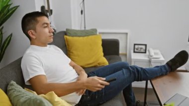 Rahat bir genç adam evdeki bir kanepede uzanmış, rahat ve modern bir yaşam sürüyor..