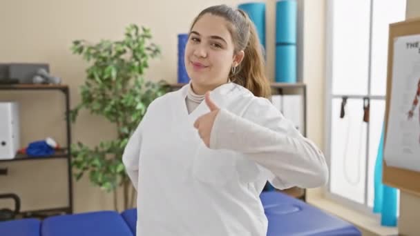 Gledelig Ung Hispanic Kvinne Sykepleieruniform Gir Tommel Opp Rehabiliteringsklinikken Glødende – stockvideo
