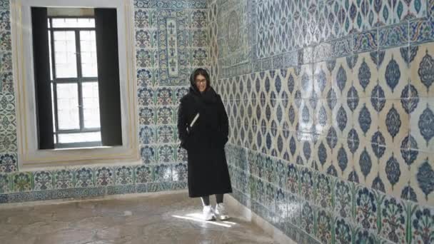 若い女性がイスタンブールの歴史的なトップカピ宮殿を探索し 彼女を取り巻くタイルを飾る — ストック動画